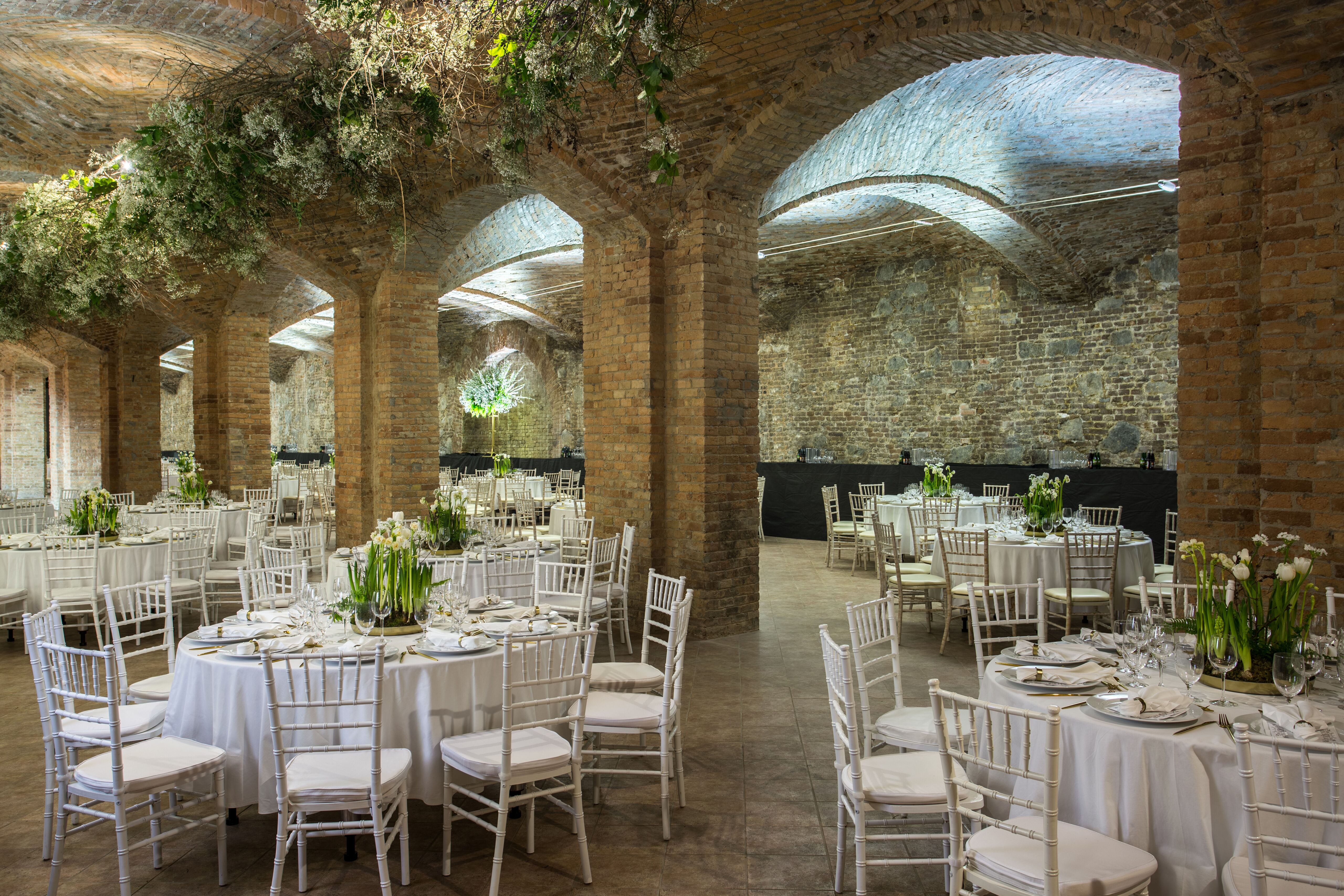 Tehlový Interiér sály plesu s oblúkovou klenbou a svetlou kvetinovou výzdobou.